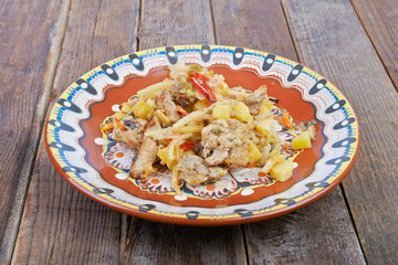 Meat with vegetables on a plate, stew on a wooden table