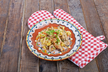 Meat with vegetables on a plate, stew on a wooden table