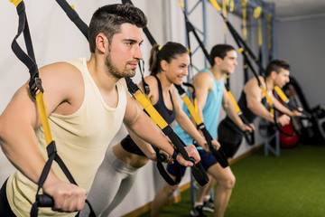 Fototapeta na wymiar People training at elastic rope in gym