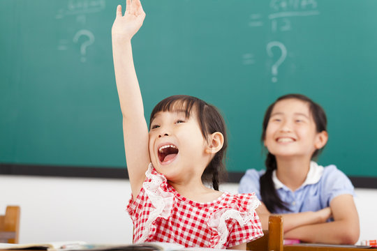 happy school children  raised hands in class