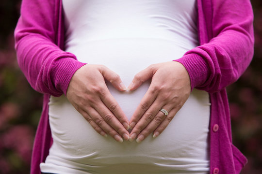 A Woman's Hands Forming a Heart Symbol on a Pregnant Belly