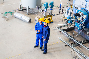 Two workers in industrial factory discussing © Kzenon