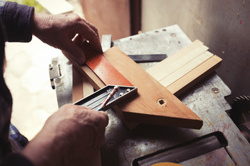 Old carpenter taking measurement of a wooden plank, retro tinted