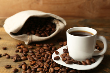 Cup of coffee with beans on rustic wooden background