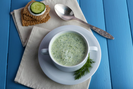 Cucumber soup in bowl on color wooden planks background