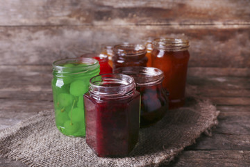 Homemade jars of fruits jam on rustic wooden background