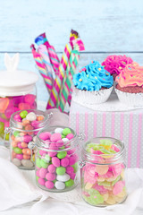 Multicolor candies in glass jars and cupcakes