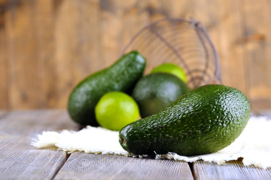 Avocado with limes on napkin on wooden background