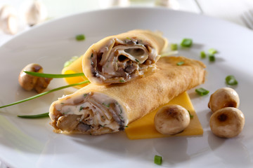 Pancakes with cream and mushrooms on wooden table, closeup