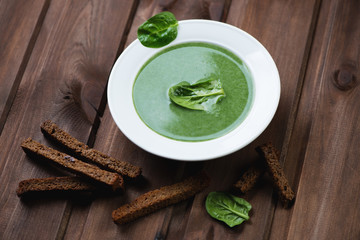 Spinach cream-soup with croutons over dark wooden background