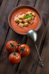 Tomato soup gazpacho with croutons, dark wooden background