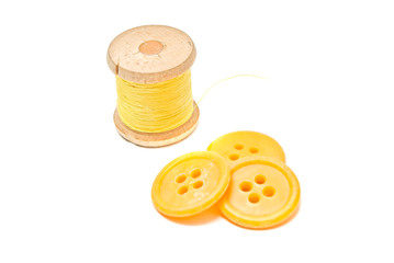 Obraz premium spool of yellow thread and plastic buttons
