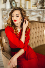 Fototapeta na wymiar The girl in a red dress with gold costume jewelry
