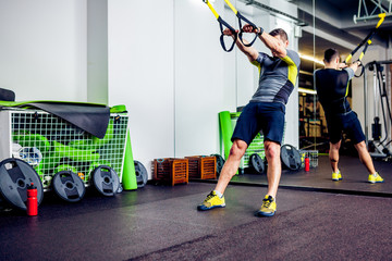 Fototapeta na wymiar Crossfit instructor at the gym doing TRX Excersise