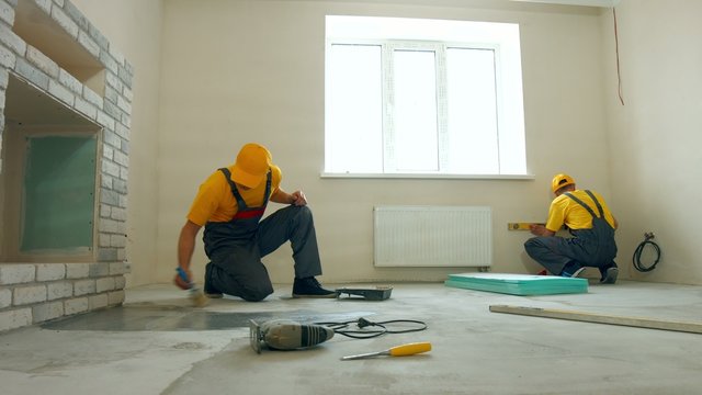 Priming floor in a large house. Workers insulated floor.