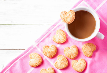 Cup of coffee and heart shaped cookies on pink dishtowel
