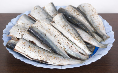 Sprats with salt and pepper ready for cooking on a plate