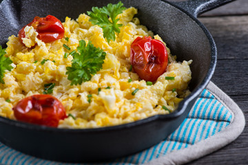 scrambled egg with grilled tomato in vintage iron pan