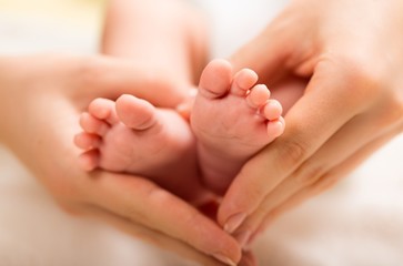 Child. Baby feet in mother hands. Tiny Newborn Baby's feet on