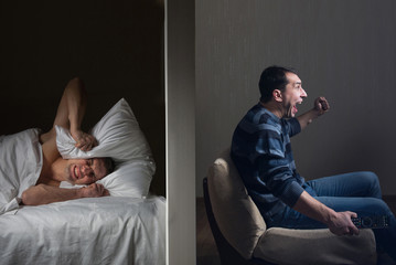 Man at night can't fall asleep because of the noisy neighbor