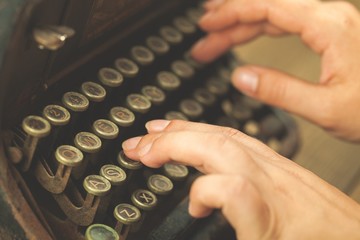 Alphabet. Hands writing on old typewriter