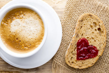Fresh coffee. Grain slice of bread with jam heart shape.