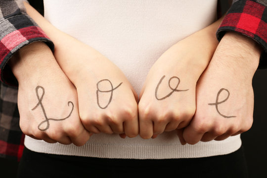 Hands of couple with inscription Love, close-up view