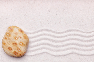 Zen garden with a orange spotted rock and wave pattern in the sa