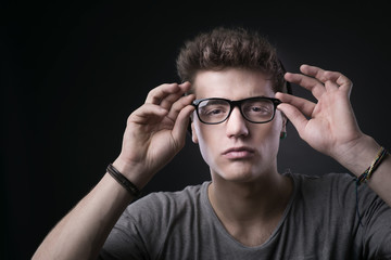 Cool young man adjusting his glasses