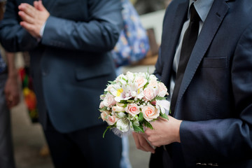 Pastel wedding bouquet with roses in groom's hands