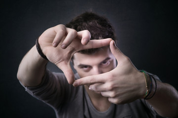 Young man framing his eyes with fingers