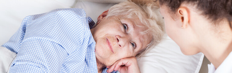 Elderly woman in bed - obrazy, fototapety, plakaty