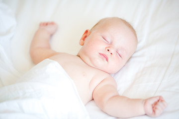 Peaceful newborn baby lying on a bed sleeping