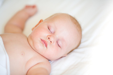 Peaceful newborn baby lying on a bed sleeping