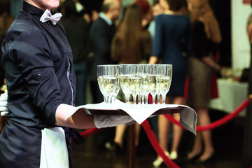 Waiter with tray and wine glasses at party