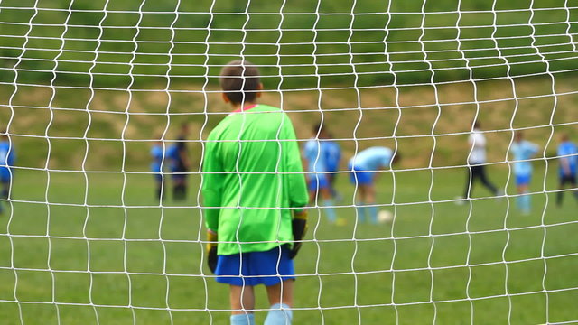 Children soccer game from behind goal net