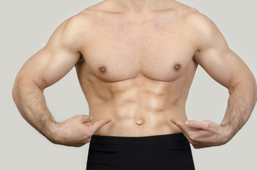 Fototapeta na wymiar Close up on man abs.Strong bodybuilder pointing to his six pack.