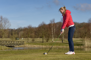 Obraz premium Frau beim Abschlag auf einem Golfplatz