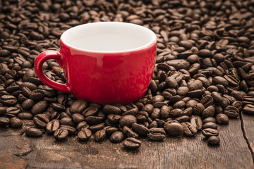 Close up of an empty red cup on top of dark roasted coffee beans