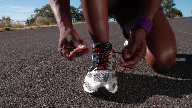 African American runner tying his laces, close up slow motion