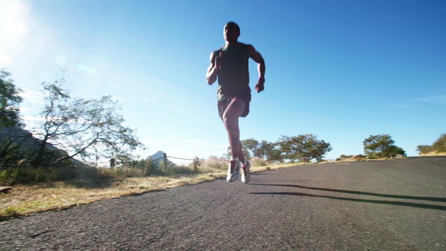 African american runner along a mountain road with morning sun flaring
