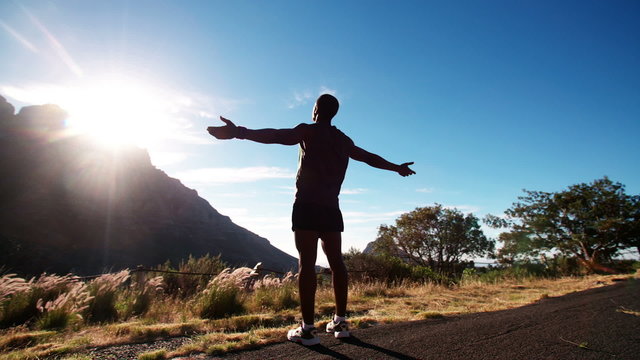 Triumphant African American athlete enjoying fitness in nature