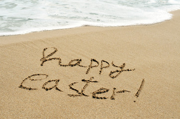 happy easter written in the sand of a beach
