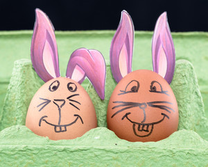 Two Easter eggs with painted faces and bunny ears