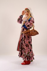 Blonde girl in folkloric dress standing with wooden basket
