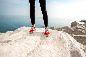 Sporty woman legs on the rocky beach