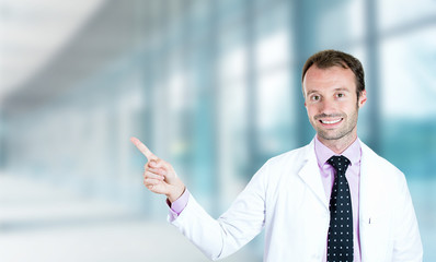 Fototapeta premium happy male doctor smiling pointing with finger away up