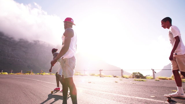 Mixed racial group of teen longboarders on road