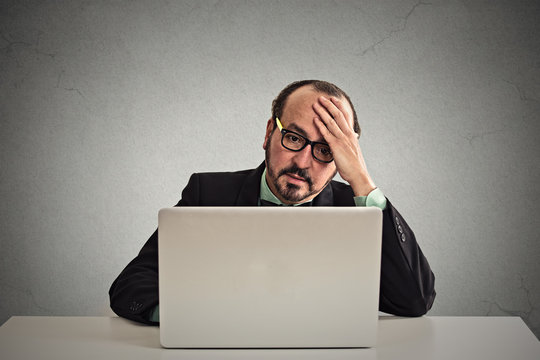 stressed displeased business man working on laptop computer