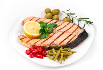 Grilled salmon steak with vegetables on plate.